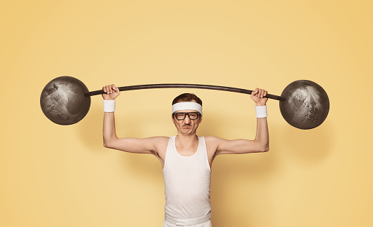 Funny retro sport nerd lifting weights over yellow background with copy space