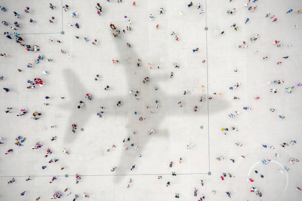 istock Aerial view of crowd with airplane shadow 1180390323