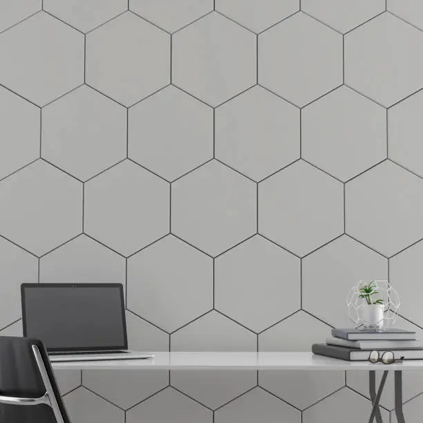 Workdesk with decoration in front of empty grey hexagon tiled wall with copy space. 3D rendered image.