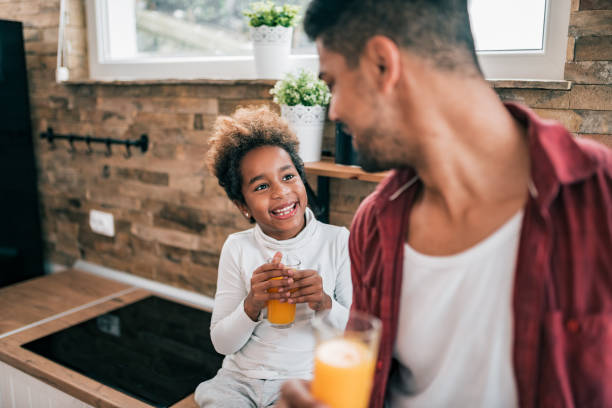istock Father and daughter drinking juice in the kitchen. 1180393939