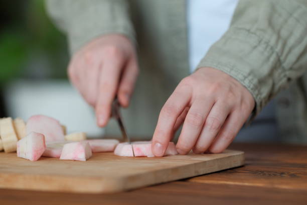 Girl cuts a peeled red fresh apple with a knife