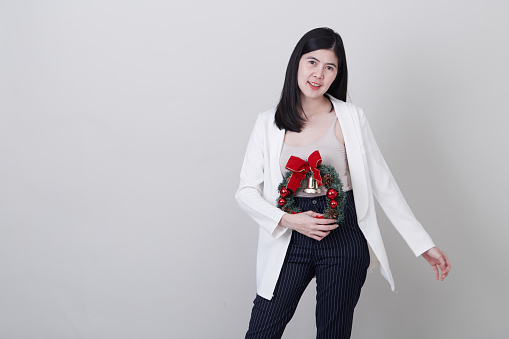Portrait of a cheerful asian woman in christmas hand holding a wreath  isolated on light gray studio banner background with copy space