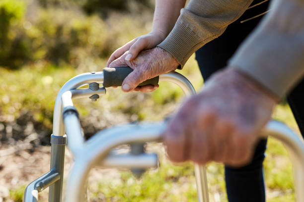 Cropped shot of an unrecognizable senior man talking a stroll outdoors with the help of his nurse and mobility walker