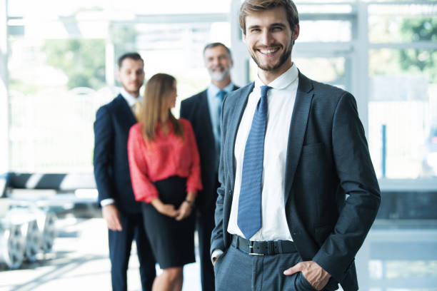istock Team leader stands with coworkers in background 1180400651
