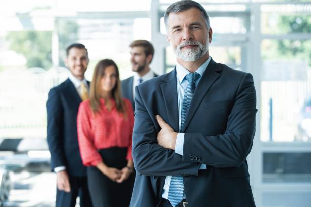 istock Proud smiling businessman standing with his colleagues at office 1180400926