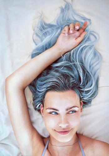 Cropped shot of an attractive young woman lying in bed with her colorful hair