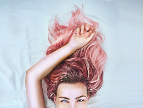 Cropped shot of an attractive young woman lying in bed with her colorful hair