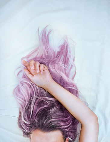 Cropped shot of an attractive young woman lying in bed with her colorful hair