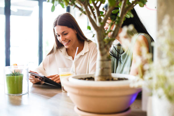 istock Two female friends using a tablet in a cafe 1180402251