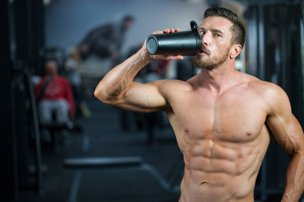 istock Strong,  man in a gym drinking protein or water from the black shaker 1180404842