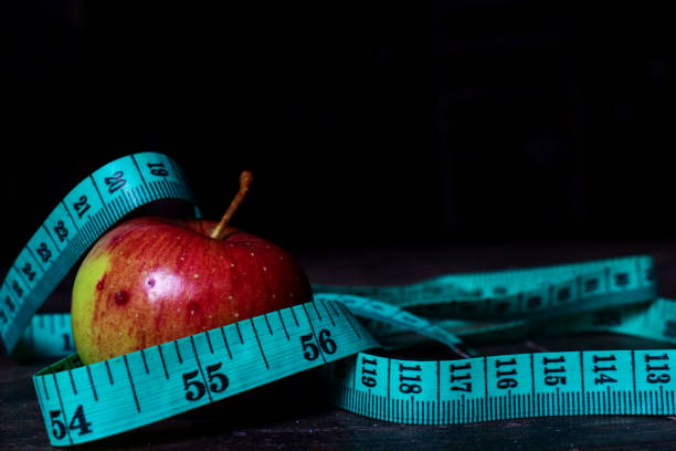 istock diet apple with measuring tape 1180408465