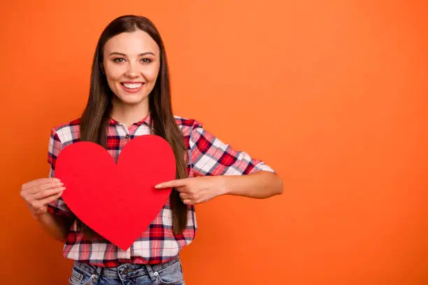 Photo of Close up photo portrait of cute pretty attractive calm charming lovely dreamy youngster holding large bright paper heart in hands asking for a date isolated vivid color background
