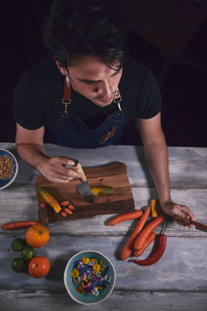 Young chef in kitchen holding knife and preparing dinner. Food concept.