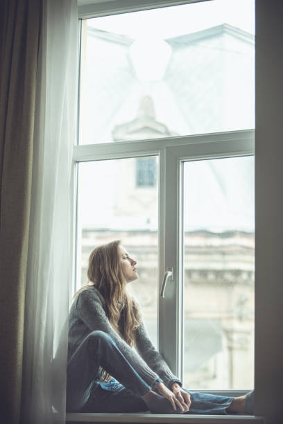 istock Beautiful young woman sitting by the window 1180421734