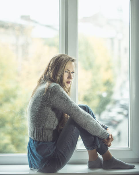 istock Beautiful young woman sitting by the window 1180421736