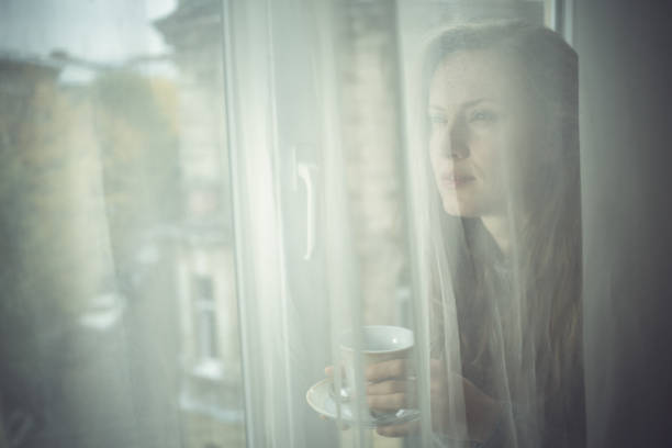 istock Beautiful woman drinking tea or coffee by the window 1180421737