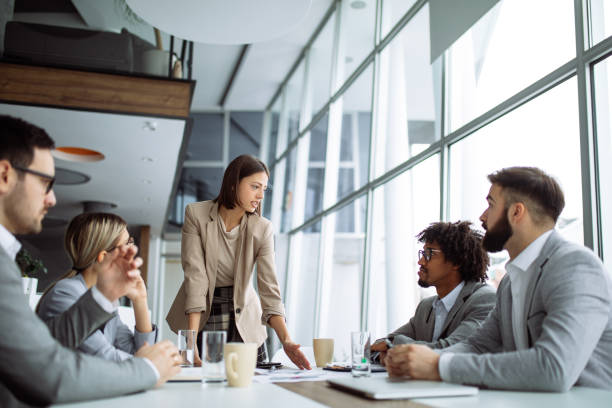 istock Female manager stands addressing team at board meeting 1180422482