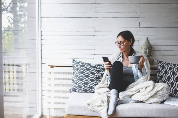 женщина средних лет сидит комфортно и наслаждается чаем - relaxation indoors reading one person стоковые фото и изображения