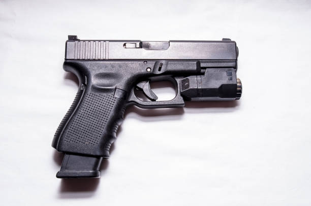istock A black semi automatic 9mm pistol with an attached flashlight under the muzzle and an extended magazine 1180438732