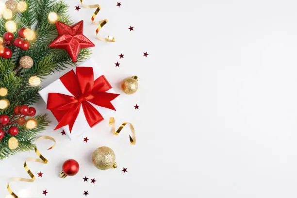 Photo of Christmas gift, fir tree branches and Christmas ornament on white background.