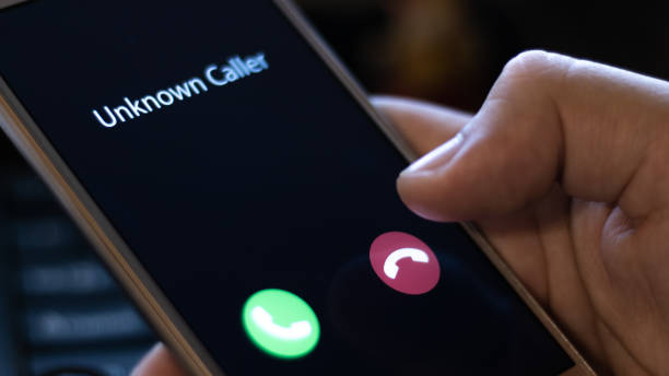 Unknown caller. A man holds a phone in his hand and thinks to end the call. Incoming from an unknown number at night. Incognito or anonymous stock photo