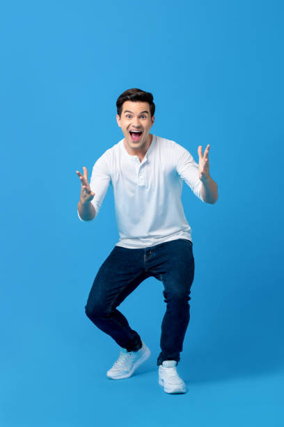 Young caucasian man in surprised gesture Young caucasian man in surprised gesture with opening hand and mouth on light blue background arms outstretched stock pictures, royalty-free photos & images