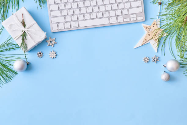 istock Flat lay christmas home office desk with pine branches and keyboard, christmas decorations on a blue background 1180444716
