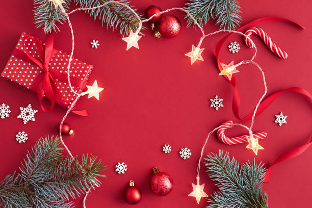 istock Flat lay frame with red christmas balls, spruce branches and and garland on a red background 1180444743