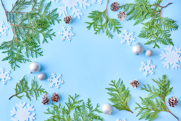 istock Flat lay christmas frame with snowflakes and evergreen tree branch on a blue background 1180444744