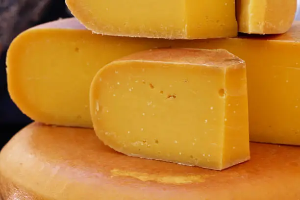 Photo of Close up cut slices and wheel of hard gouda cheese