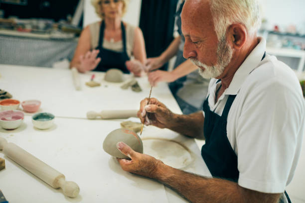 istock Senior Man Decorating Ceramics Bowl At Ceramics Workshop 1180447251