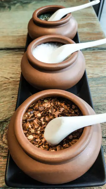 Spices in mini claypots with porcelain spoon