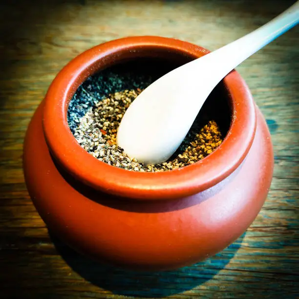 Crushed pepper corns in a small claypot with a porcelain spoon