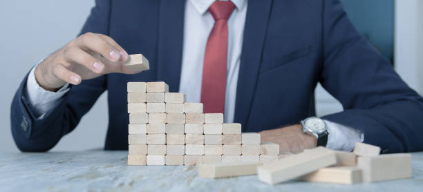 istock businessman makes a pyramid with empty wooden cubes; business concept 1180448550