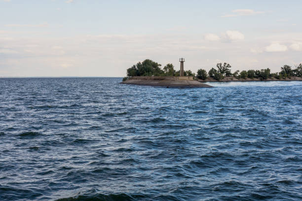 istock Lighthouse on edge of  concrete breakwater on  wide river 1180448931
