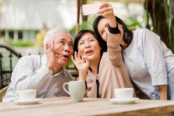 tres amigos mayores felices tomando un selfie en una cafetería - mobile phone coffee shop group of people women fotografías e imágenes de stock