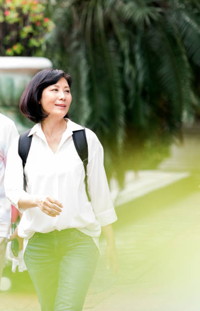 istock Candid portrait active senior woman walking through public park 1180450732