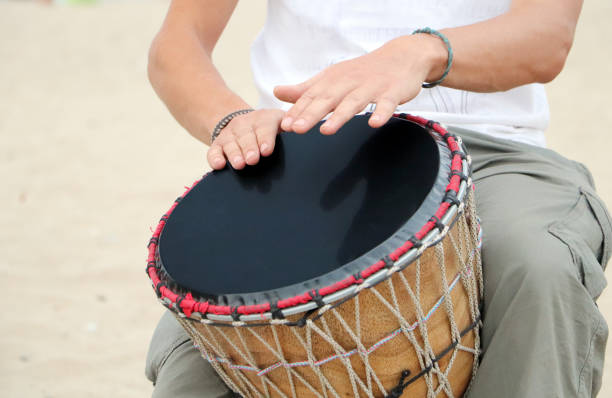 istock A man plays an African djembe drum against a blue sky. Creativity, rest and relaxation. Ethnic musical instrument against the sky as a concept of creative flight. 1180453946