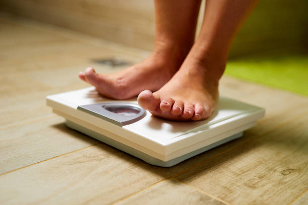 istock Female bare feet on weight scale in a bathroom 1180456813
