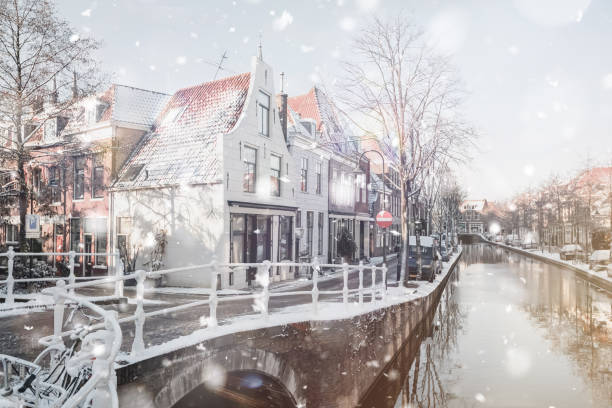 Delft Netherlands residential district Delft Netherlands Houses and Canal in residential district view at winter snowstorm. Pastel trendy toning. Beautiful inspiring moody faded scenery delft winter netherlands snow stock pictures, royalty-free photos & images