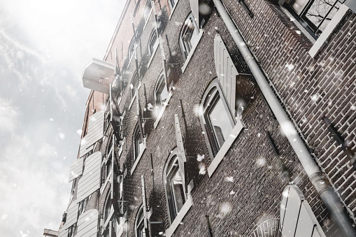 Amsterdam old house view at winter snowstorm. Pastel trendy toning. Upward glance. Beautiful inspiring moody faded scenery