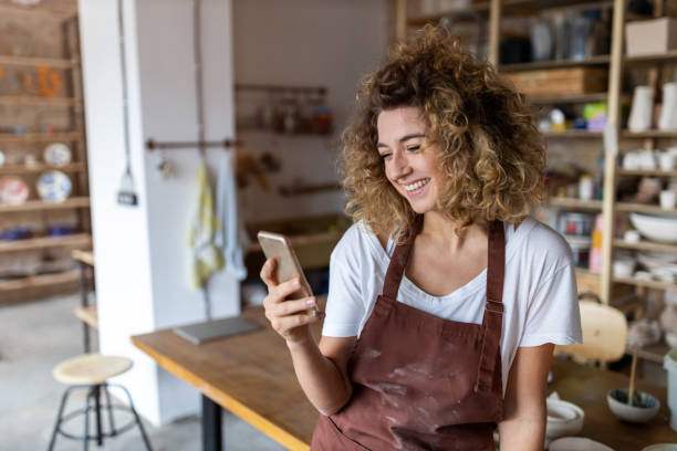 istock Female potter with smartphone in art studio 1180465978