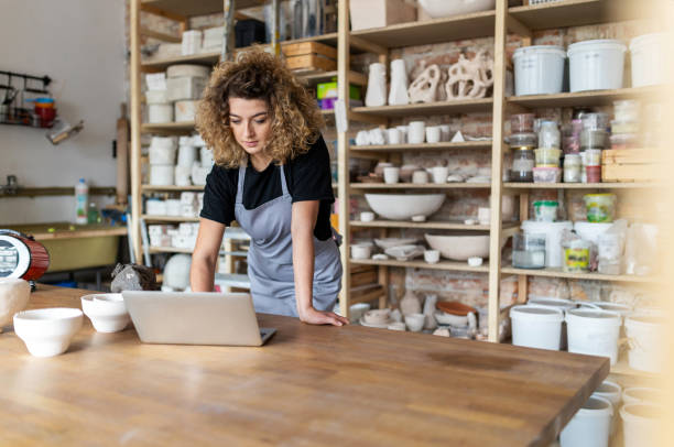 istock Female potter using laptop in art studio 1180466058