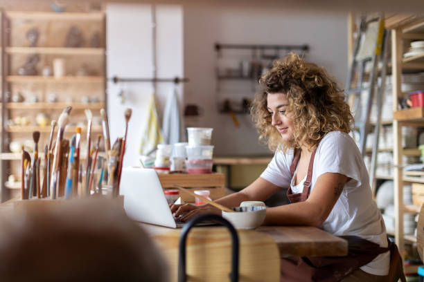 istock Female potter using laptop in art studio 1180466108