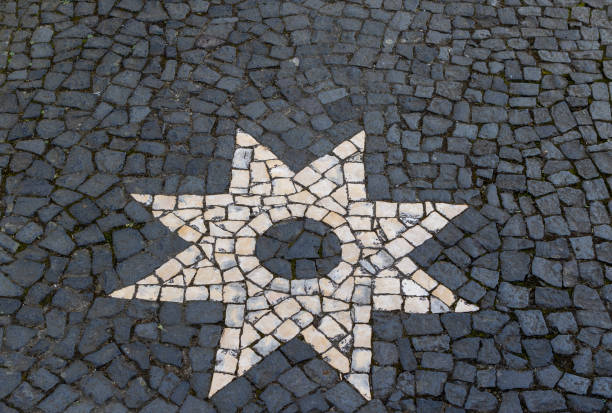 Surface of traditional cobble stone pavement in  Azores, Portugal. Stone abstract textured background with eight pointed star mosaic ornament