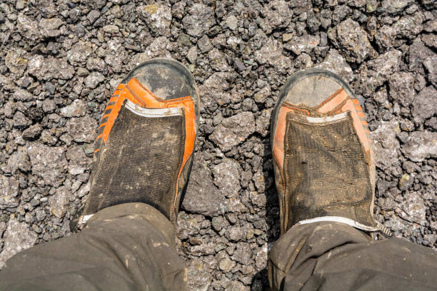 istock Muddy mountaineering boots after a mountain trip presented on crushed asphalt. 1180471343