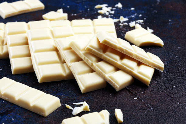 istock white broken chocolate and cocoa bar. Pieces of white chocolate on rustic background 1180475756