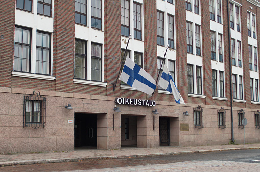 Facade of a courthouse in Hämeenlinna, Finland with two national flags half mast.