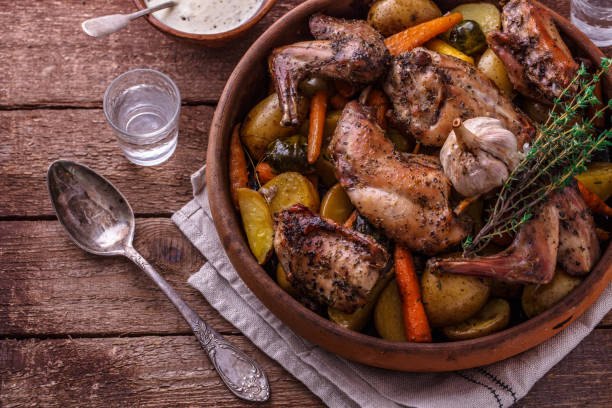 lapin cuit au four avec des légumes et des herbes de racine, modèle rustique - lapin viande de gibier photos et images de collection