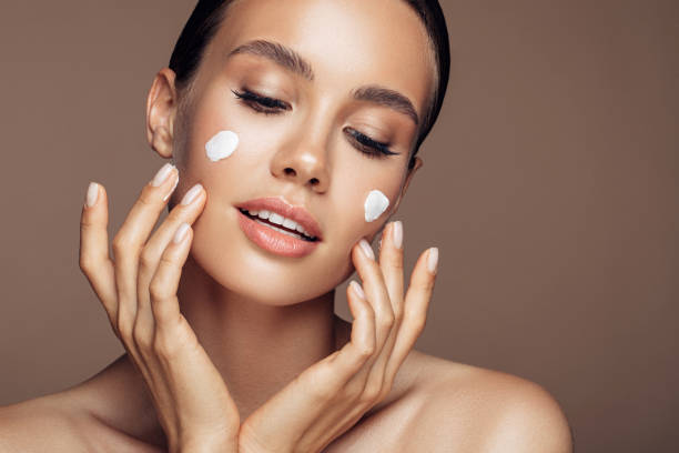 istock Beautiful woman applying cream on her face 1180487029